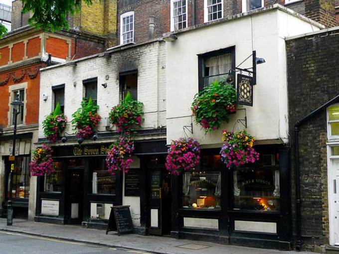 Outside of a pub with flower pots hanging from the wall